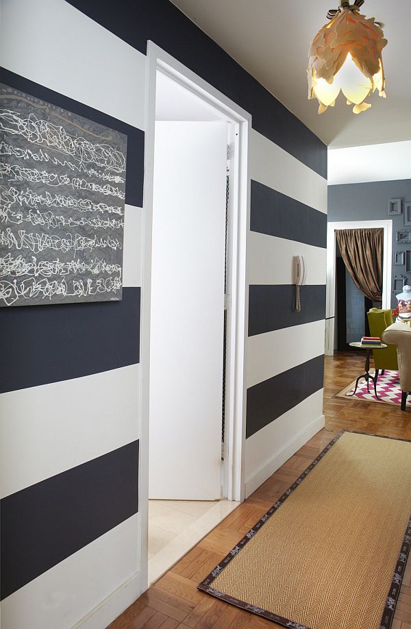 an entryway with a black and white accent wall, a chalkboard, a jute rug and a catchy floral ceiling lamp