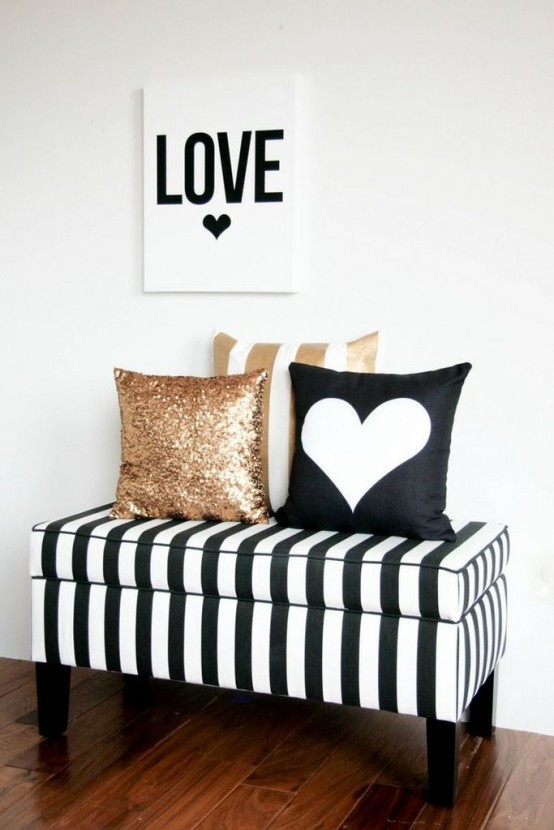 a black and white striped storage bench with black and gold sequin pillows is a glam piece for an entryway or a living room