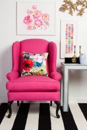 a black and white stripe rug, a hot pink chair and gold touches in the space make it glam and fun