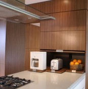 a sleek cabinet with retracting shelves and appliances and fruits in a bowl for a minimalist kitchen