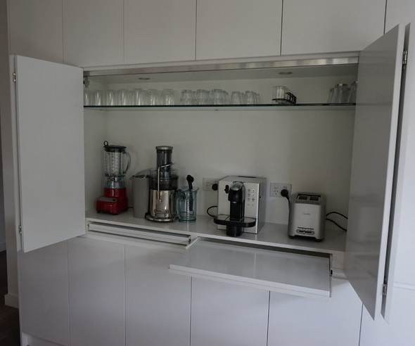 a white cabinet with a glass and retractable shelves and several different appliances is a real cooking and coffee station