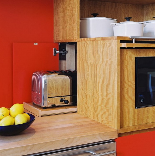 a chic toaster on a retracting board hidden in the back part of a cabinet with built in appliances