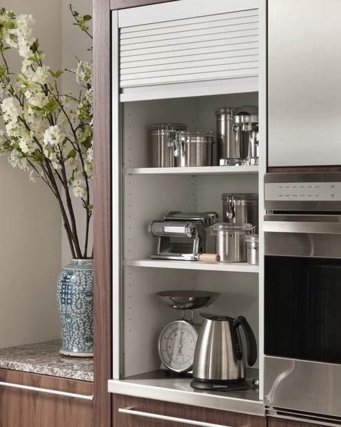 a narrow cabinet with shelves holding cookware, pots, some appliances can be closed with a shutter