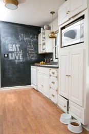 a neutral farmhouse kitchen with a chalkboard accent wall, metallic pendant lamps and dark countertops