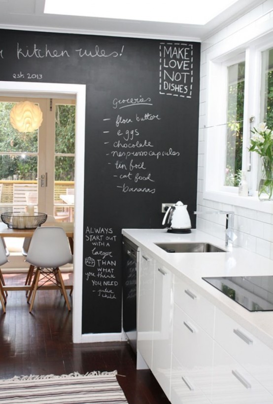 a sleek white kitchen and an accent chalkboard wall that can be used for practical purposes and adds a contrasting touch