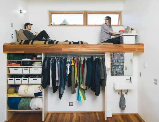 an open closet with hangers, boxes and open shelves and a platform with a home office and a daybed on top