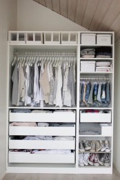 a small fully organized closet with drawers, open and closed compartments, clothes hangers and boxes
