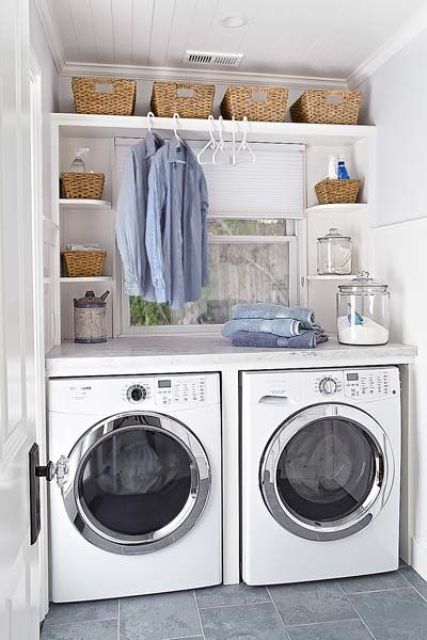 a tiny white laundry that features only the washing machine and dryer, a couple of shelves with baskets and clothes hangers
