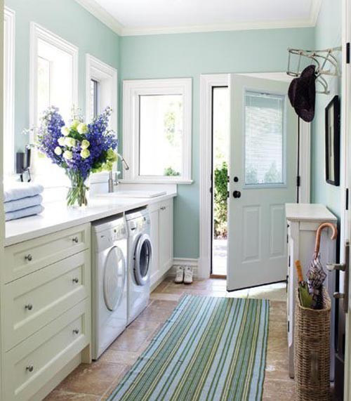 a light blue laundry with neutral shaker style cabinets, white countertops, a small console table and dresser, a basket with umbrellas