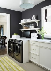 a black and white farmhouse with black walls, chic neutral cabinets, a black washing machine and a dryer and open shelves