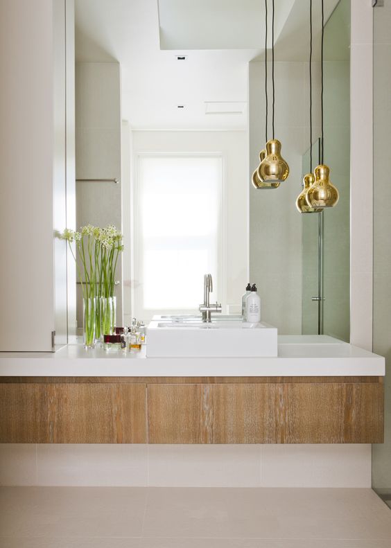 gold shaped pendant lamps accent the bathroom giving it a chic look and a timeless feel as metallics are timeless