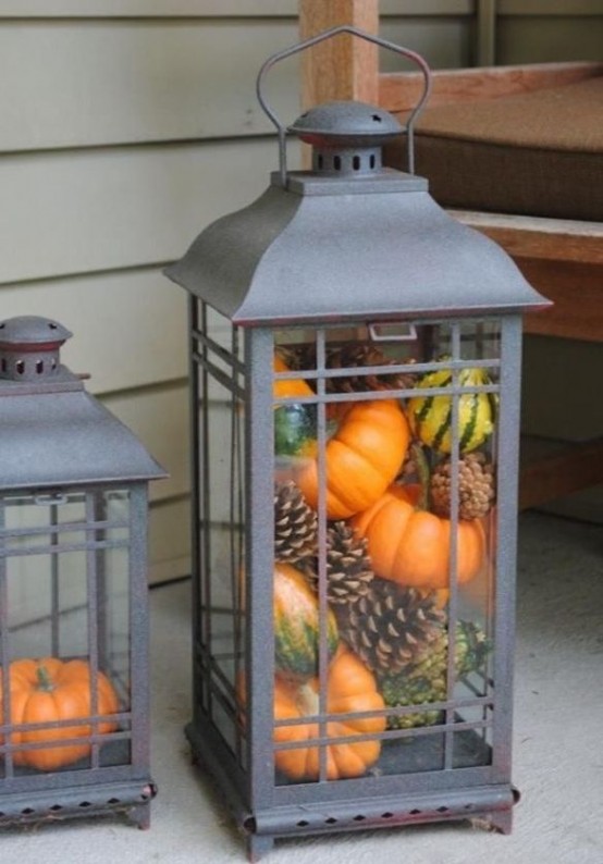 a large candle lantern filled with pinecones, gourds and pumpkins is a lovely idea to decorate your front porch