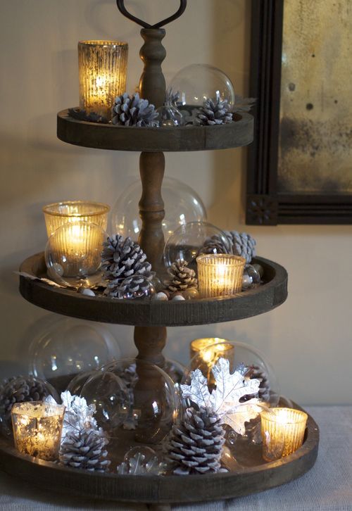 a wooden stand with snowy pinecones, acorns, nuts, candle lanterns and glass bubbles for chic fall decor