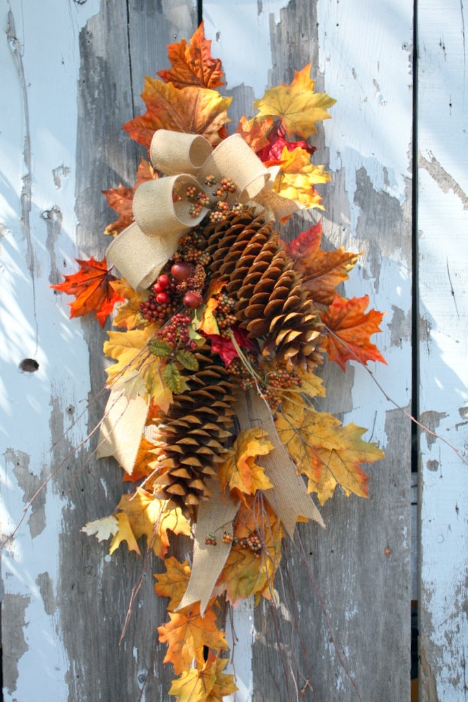 a fall posie with fall leaves, pinecones, a burlap bow is a fun and cool fall decoration to hang anywhere