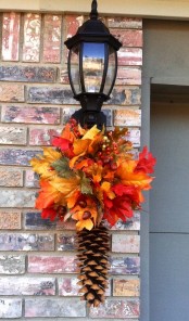 a bright fall decoration of a pinecone, bold faux leaves and berries can accent your front door or any other space