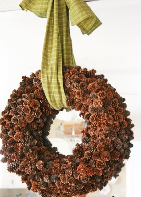 a large and thick pinecone wreath with a green plaid ribbon is a cool decoration for your autumanl front door