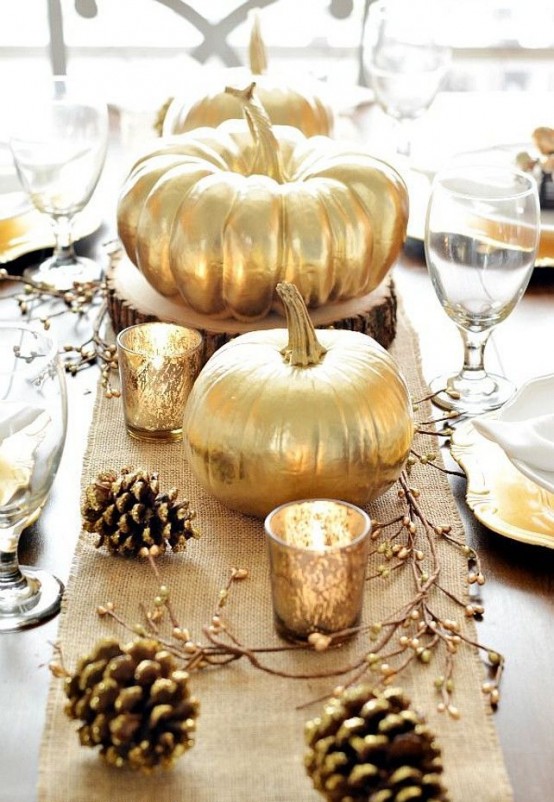 fall table decor wuth a burlap table runner, gilded pinecones, candles in gold mercury glass candleholders and gilded pumpkins for a fall party or Thanksgiving