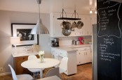 a small all-white kitchen with a countertop separating the cooking and dining areas with a round table and chairs