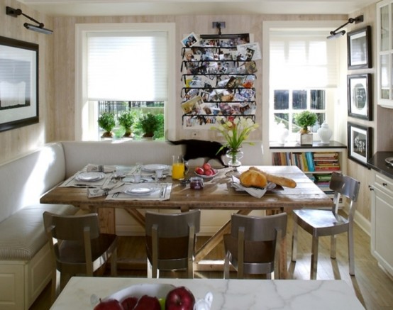 a dining space with an L-shaped seating and a table plus artworks and a kitchen island that separates the spaces