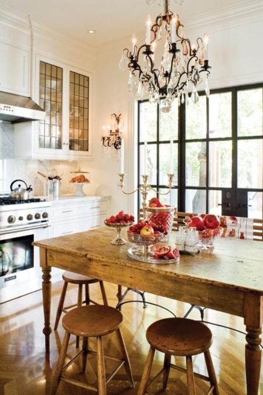 a small eclectic kitchen with white farmhouse cabinets, a vintage wooden dining set and a large crystal chandelier