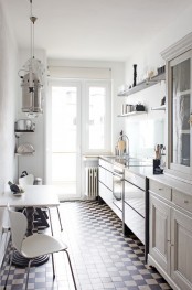 a vintage Scandinavian kitchen in white with open shelving and cabinets, a rustic space with chairs and a carved wooden table plus a mosaic floor