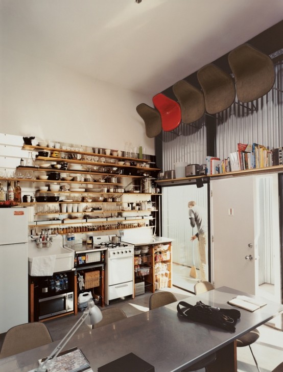 a small yet functional kitchen with open cabinets, an oversized shelving unit taking the whole wall and some appliances