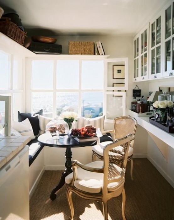 a small farmhouse kitchen with a view, an L-shaped bench, a round table, vintage chairs, glass cabinets and shelves