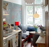 a tiny eclectic kitchen with some cabinets and a cozy nook by the window with a hexagon table