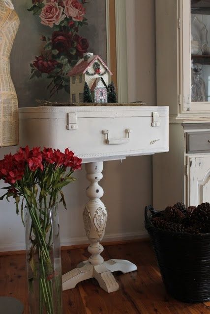 a vintage white suitcase placed on a tall vintage leg makes up a nice vintage or shabby chic side table for any space