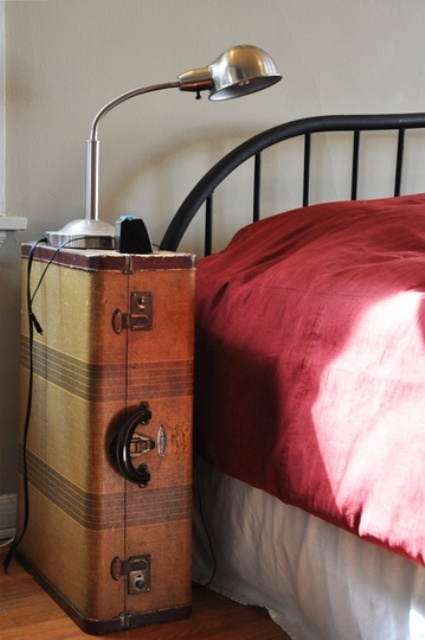 a vintage suitcase placed on its side is a cool idea of a bedside table that features some storage space and you may place a lamp on top