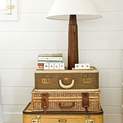 a stack of vintage suitcases of various sizes is a cool substitution for a side table and a table lamp and some books can be placed on top