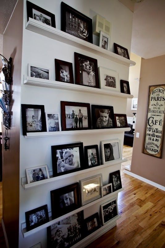 an oversized gallery wall with white ledges and black and white photos in mismatching black and white frames is a timeless idea