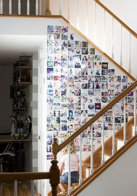 a staircase side fully covered with colorful family photos without frames is a stylish idea to use usually an unused surface