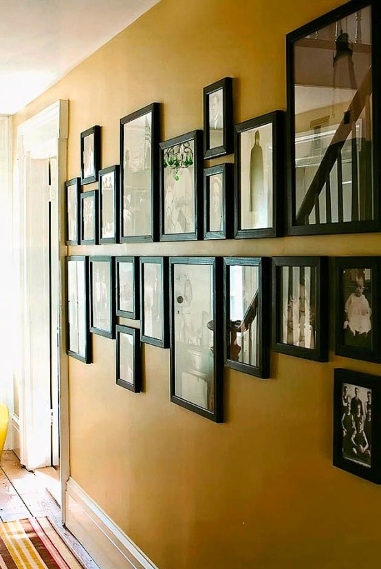 una elegante pared de galería vintage de fotos en marcos negros a juego que cuelgan en dos filas horizontales se ve elegante