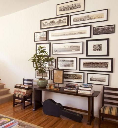 a large gallery wall with black and white photos in black frames is a cool decoration for a modern entryway