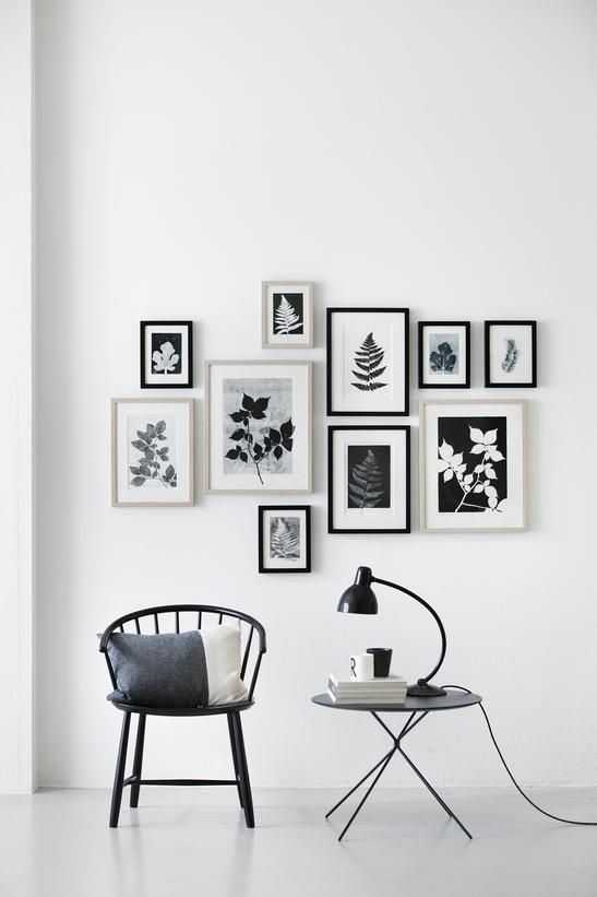 a chic gallery wall with black and white photos in black and white frames placed with a bit of chaos