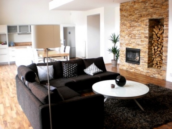 a faux stone wall with a built-in fireplace and a niche with firewood is a lovely idea for a modern space and it adds coziness to it