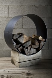 a cool modern firewood stand of a rough piece of wood and a metal circle that holds firewood is a very bold idea