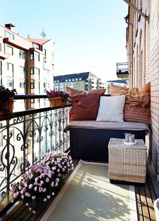 a bright summer balcony with wicker furniture, potted blooms and colorful textiles looks cute and very inviting