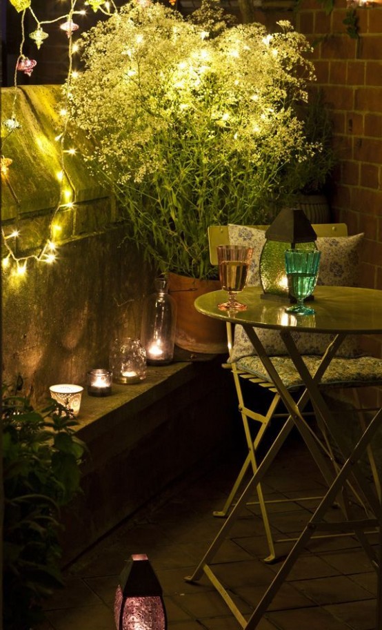 simple summer balcony decor with potted greenery and blooms, with candles and lights and vintage metal furniture