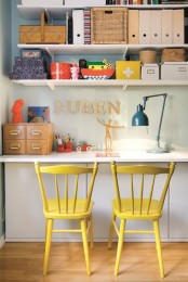 a neutral home office with open shelves, a wall-mounted desk, with bright yellow chairs and some colorful boxes for a bolder look