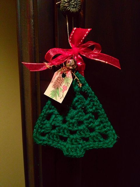 a green knit Christmas tree ornament with a red bow and bells is a pretty idea to decorate a Christmas tree, a mantel or use it as a tag for gifts