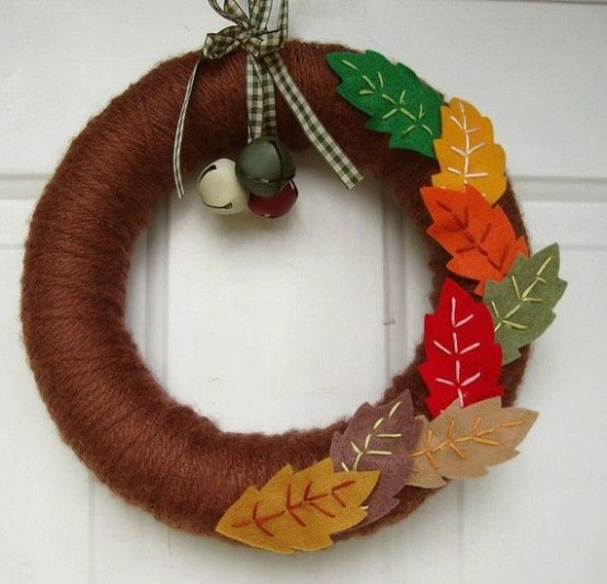 a bold fall wreath covered with brown yarn, with colorful fabric leaves and some bells is a fun and creative decoration