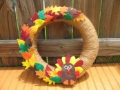 a bright fall wreath covered with twine, with colorful fabric leaves and a fabric turkey is a bold decoration