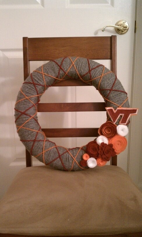 a yarn fall wreath covered with grey, rust and orange yarn, fabric flowers and monograms to personalize your front door