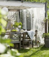 an outdoor rustic dining space with mosquito net curtains around that help to keep the space welcoming and comfortable