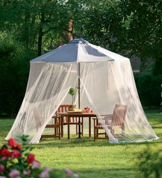 an outdoor rustic dining space covered with an oversized mosquito net with a tent helps to avoid sunshine, bugs and even rain