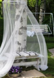 a bench with pillows and a mosquito net over it makes up a cozy and welcoming nook for relaxing