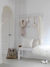 a white shabby chic meets Nordic entryway with a holder on the wall and a bench with faux fur