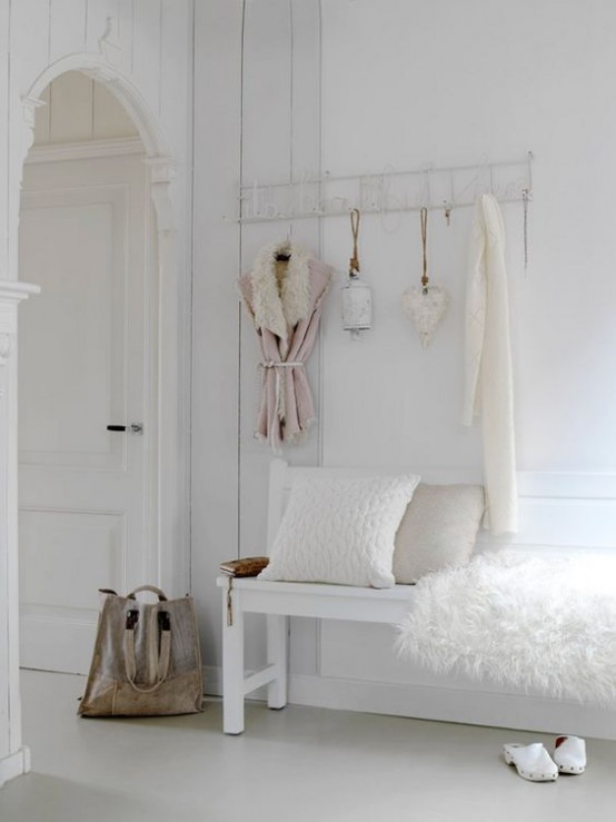 a white shabby chic meets Nordic entryway with a holder on the wall and a bench with faux fur